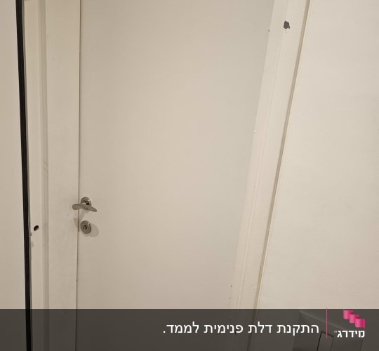 דלת לבנה עם ידית מתכת וקיר לבן